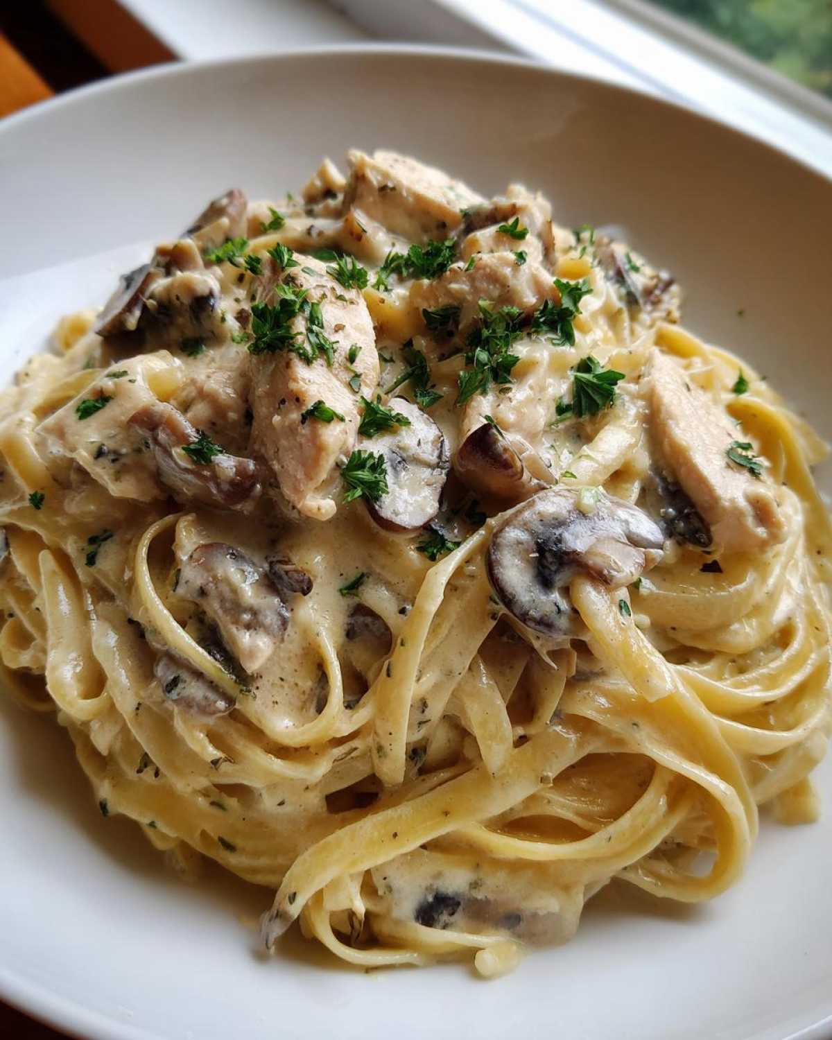Close-up of rich Creamy Mushroom Garlic Pasta with Chicken, topped with fresh parsley.