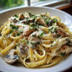 Close-up of Creamy Mushroom Garlic Pasta with Chicken featuring fettuccine, sliced chicken, mushrooms, and parsley garnish.