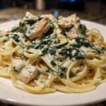 Close-up of a serving of Creamy Spinach Chicken Pasta with Alfredo Sauce, featuring spaghetti, chicken chunks, and wilted spinach.