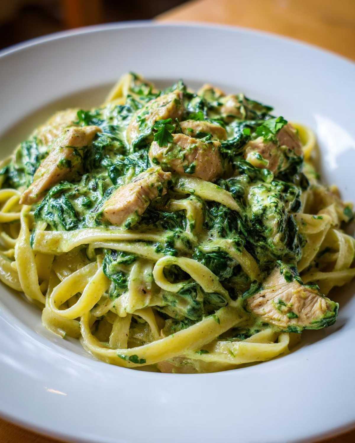 Close-up of fettuccine pasta tossed in a rich, creamy spinach sauce with chunks of chicken, representing Creamy Spinach Chicken Pasta with Garlic.