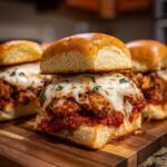 Close-up of a Crispy Chicken Parmesan Slider with melted mozzarella cheese and marinara sauce on a brioche bun.