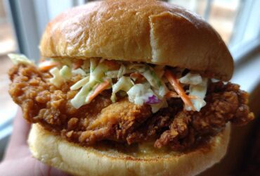 A close-up shot of a perfectly assembled Crispy Chicken Sandwich with Creamy Slaw on a toasted brioche bun.