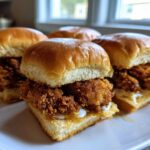 Four Crispy Chicken Sliders with Honey Mustard sauce served on a white plate.