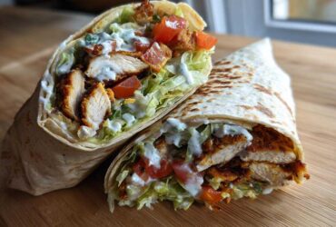 Two halves of a Crispy Chicken Wrap with Creamy Ranch Sauce, showing seasoned chicken, lettuce, and tomatoes inside a toasted tortilla.