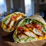 Cross-section of a Crispy Chicken Wrap with Honey Garlic Sauce, showing crispy chicken, lettuce, and tomatoes.