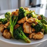 A close-up of Garlic Butter Chicken and Broccoli Stir Fry served on a white plate.