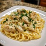 A close-up of creamy Garlic Butter Chicken Pasta with chunks of seasoned chicken, topped with parsley.