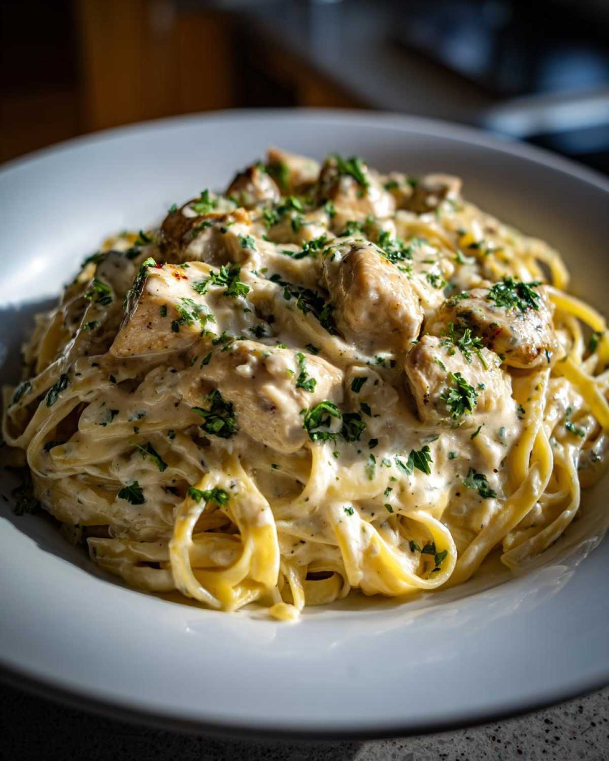 A close-up of rich Garlic Butter Chicken Pasta with cream sauce, topped with fresh parsley.