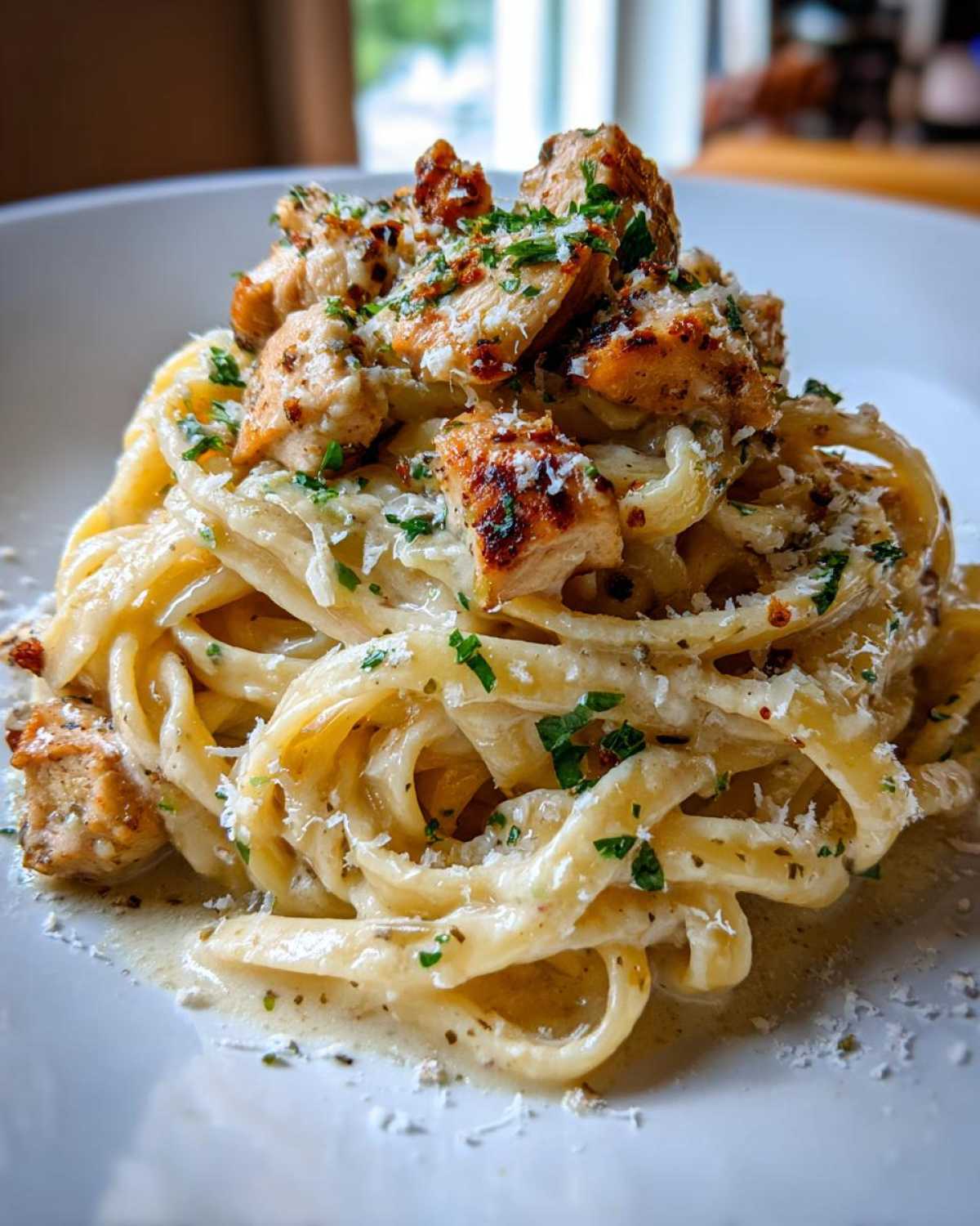 Close-up of creamy Garlic Butter Chicken Pasta with Parmesan, topped with grilled chicken pieces and fresh parsley.