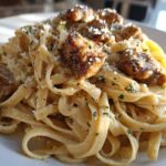 Close-up of creamy Garlic Butter Chicken Pasta with Parmesan, featuring fettuccine noodles and seared chicken pieces.