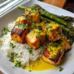 Close-up of seared Garlic Butter Salmon Bites served over white rice with asparagus and topped with parsley.