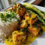 Close-up of Garlic Butter Salmon Bites served over white rice with asparagus and rich yellow sauce.