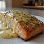 A perfectly cooked fillet of Garlic Butter Salmon generously topped with creamy lemon sauce and herbs.