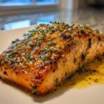 A perfectly cooked fillet of Garlic Butter Salmon with crispy edges, glistening with melted butter and herbs.