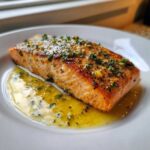 A perfectly cooked fillet of Garlic Butter Salmon with Lemon Garlic Sauce resting in a pool of buttery sauce.