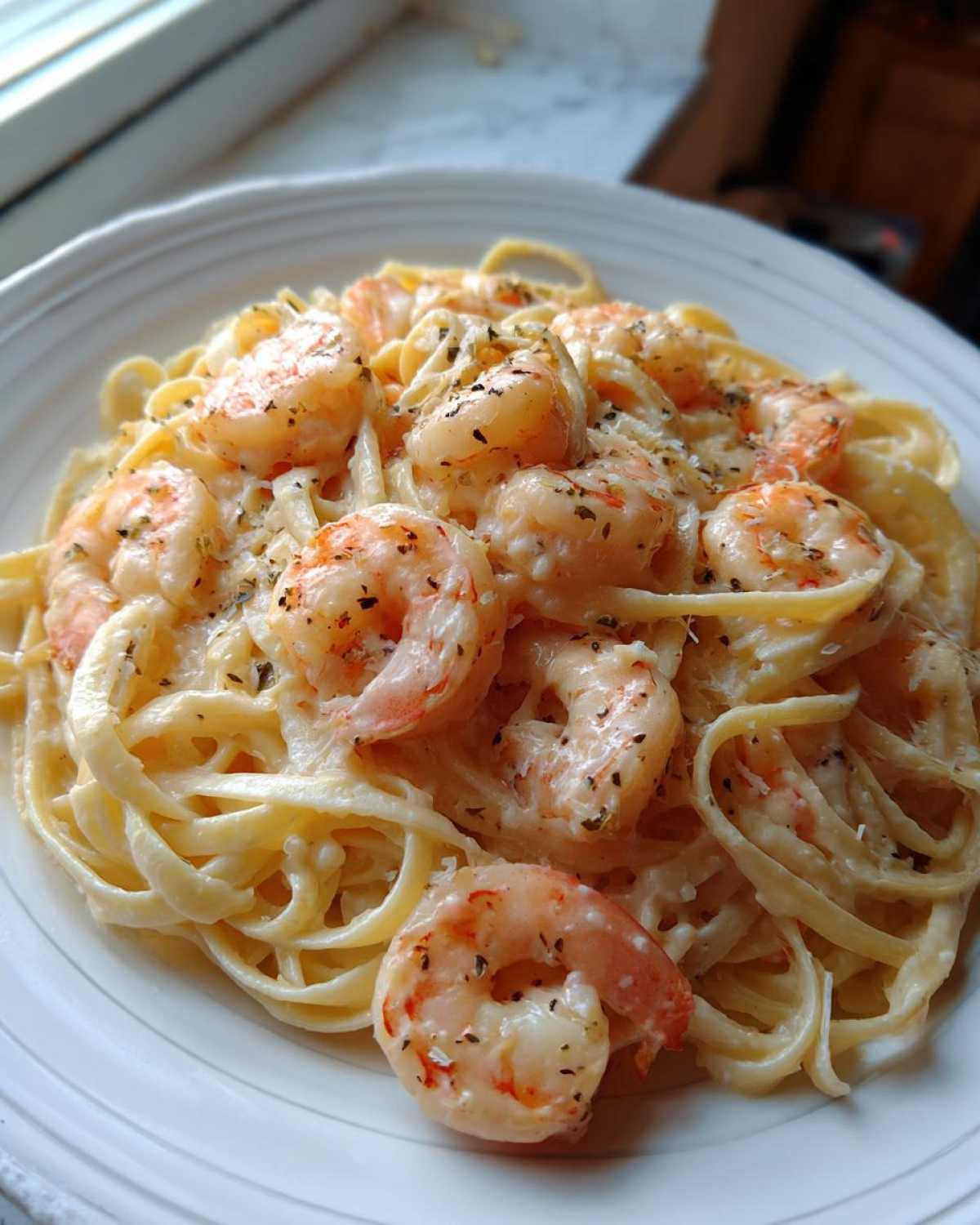 A close-up of rich Garlic Butter Shrimp Alfredo Pasta with fettuccine coated in creamy sauce and topped with seasoned shrimp.