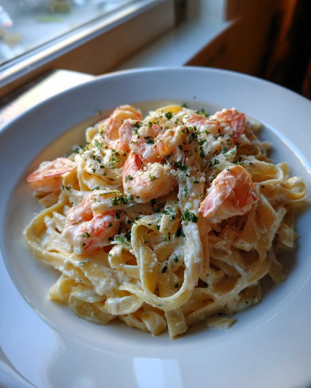 A close-up shot of rich Garlic Butter Shrimp Alfredo Pasta with fettuccine, topped with shrimp and parsley.