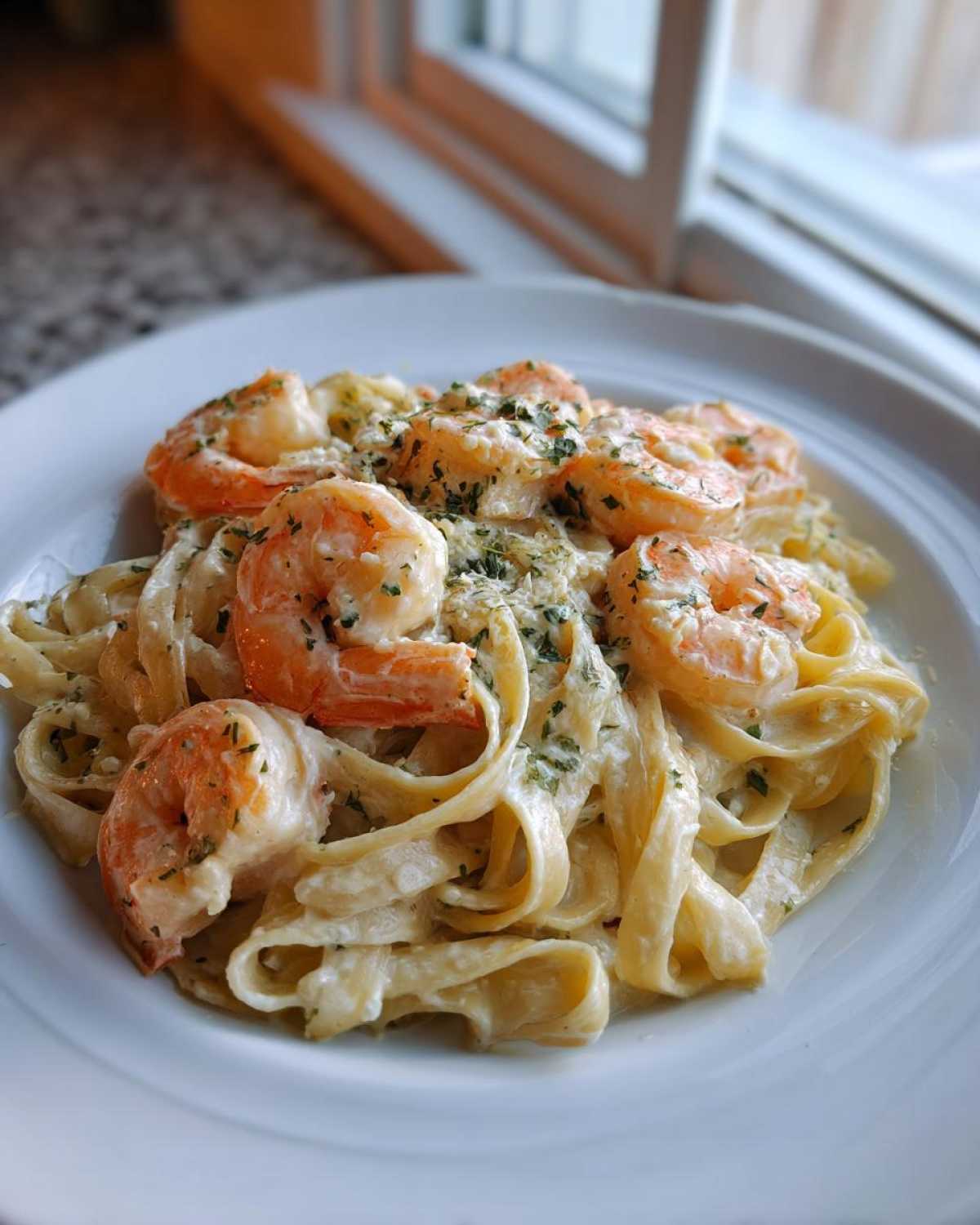 A close-up of creamy Garlic Butter Shrimp Alfredo Pasta topped with perfectly cooked shrimp and parsley.
