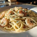 Close-up of a white bowl filled with Garlic Butter Shrimp Pasta with Cream Sauce, topped with parsley.