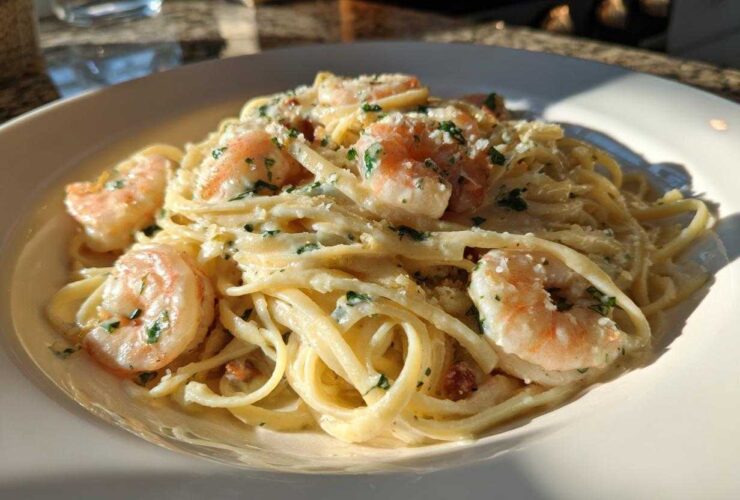 Close-up of a white bowl filled with Garlic Butter Shrimp Pasta with Cream Sauce, topped with parsley.