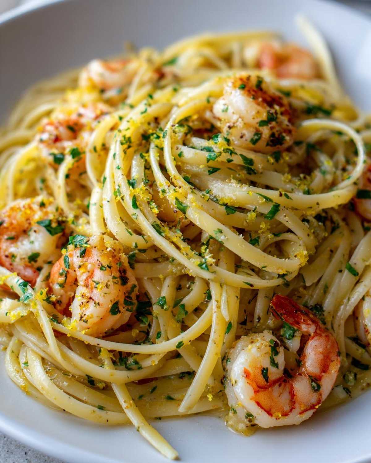 Close-up of vibrant Garlic Butter Shrimp Pasta with lemon flavor, topped with fresh parsley and bright yellow lemon zest.