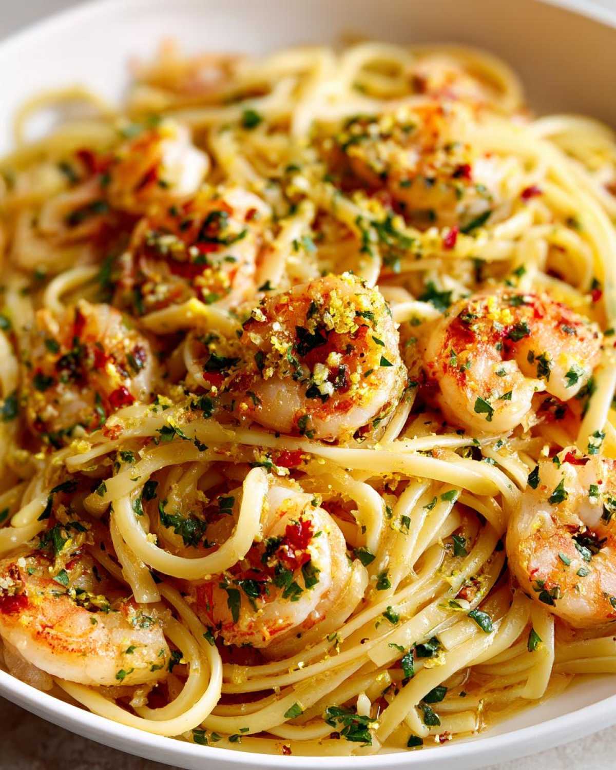 Close-up of a bowl of Garlic Butter Shrimp Pasta with Lemon Flavor, topped with parsley and lemon zest.
