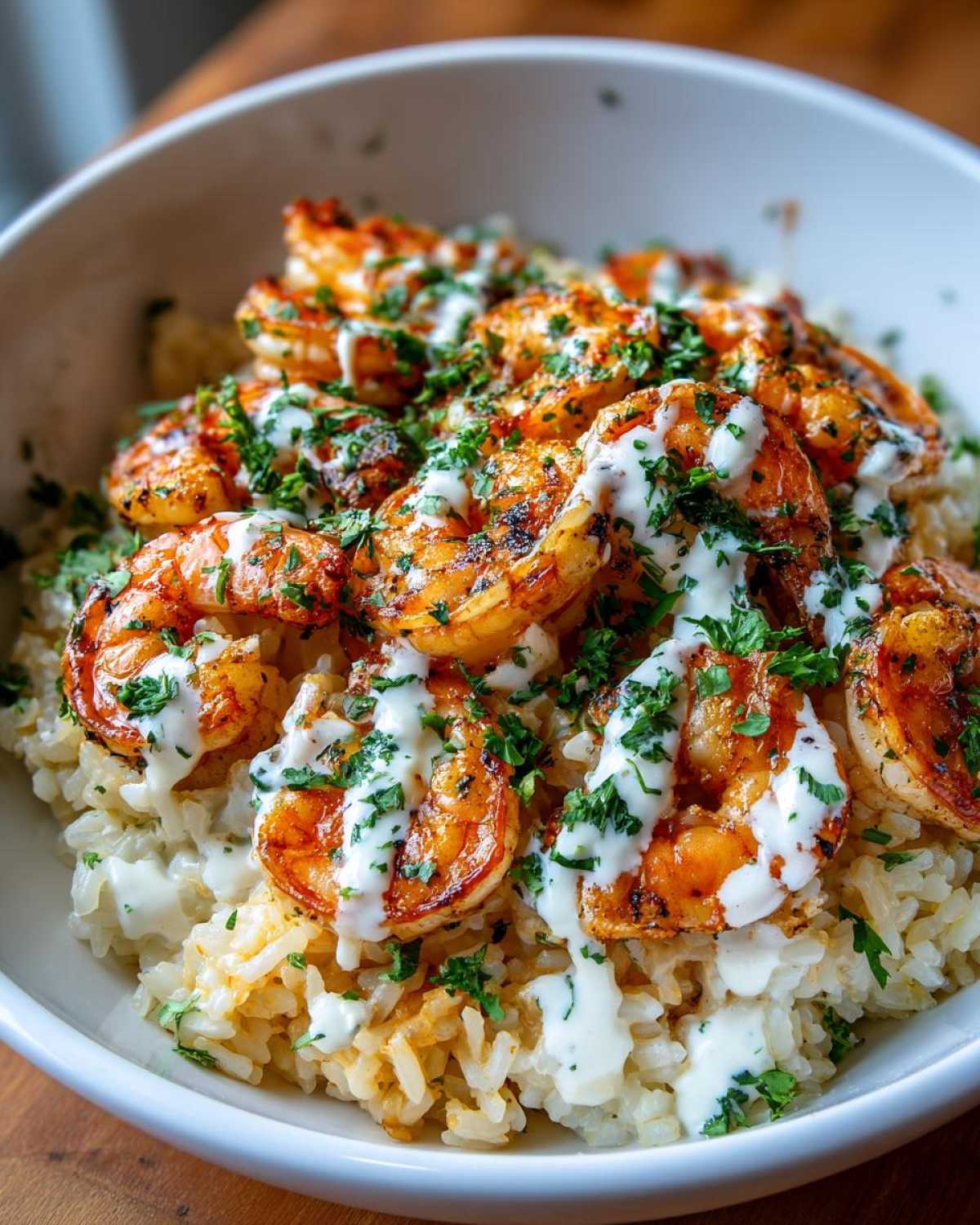 Close-up of a Garlic Butter Shrimp Rice Bowl topped with creamy garlic sauce and fresh parsley.