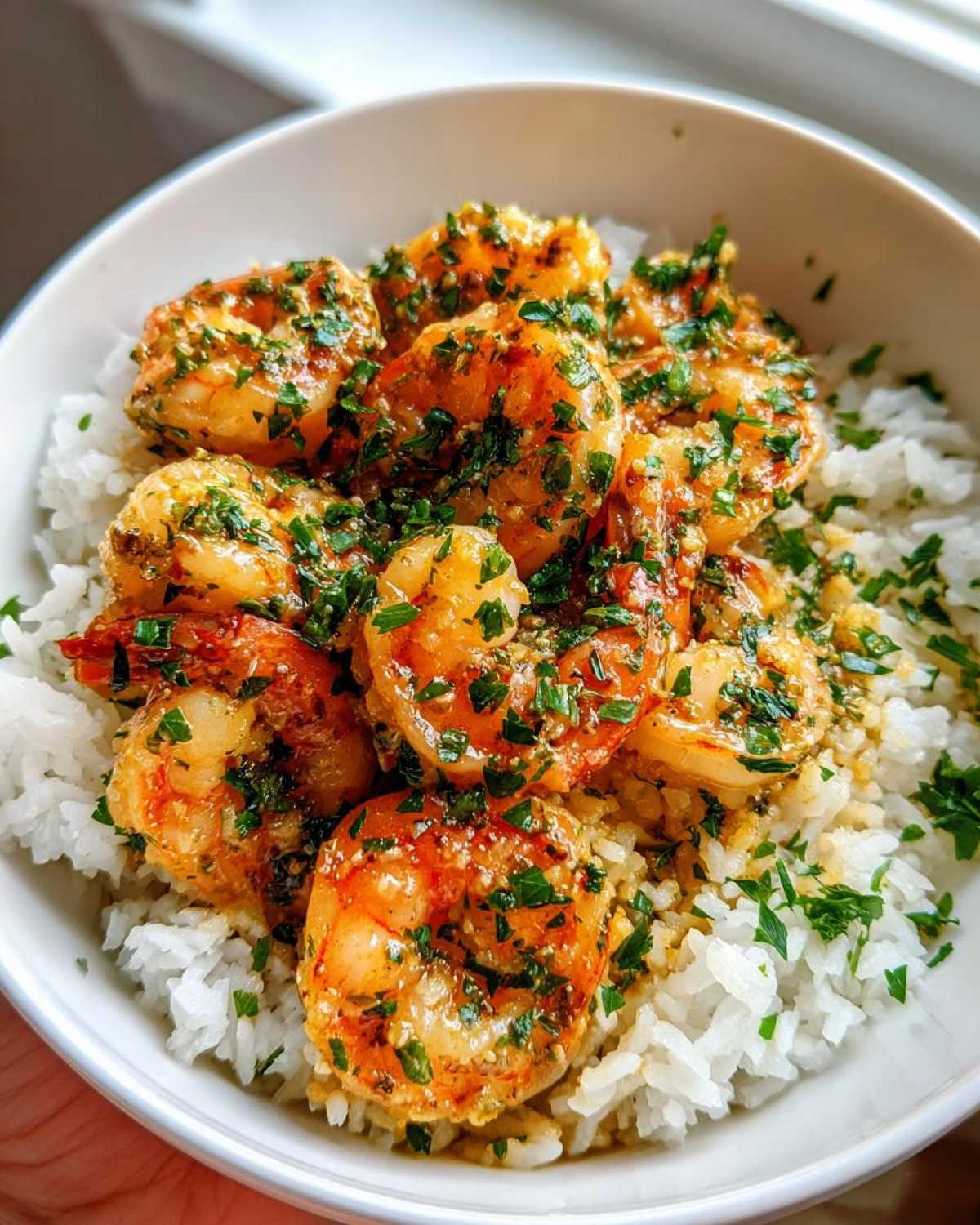 Close-up of a Garlic Butter Shrimp Rice Bowl, featuring plump shrimp coated in garlic butter sauce and fresh herbs over white rice.