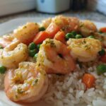 Close-up of Garlic Butter Shrimp with Rice and Veggies, featuring plump shrimp coated in garlic butter sauce over white rice with peas and carrots.