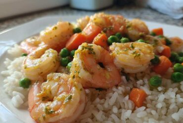 Close-up of Garlic Butter Shrimp with Rice and Veggies, featuring plump shrimp coated in garlic butter sauce over white rice with peas and carrots.