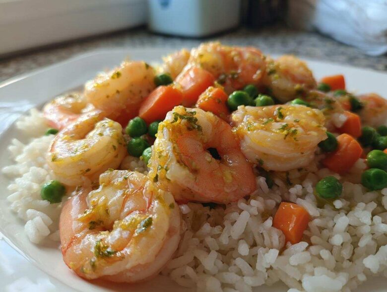 Close-up of Garlic Butter Shrimp with Rice and Veggies, featuring plump shrimp coated in garlic butter sauce over white rice with peas and carrots.