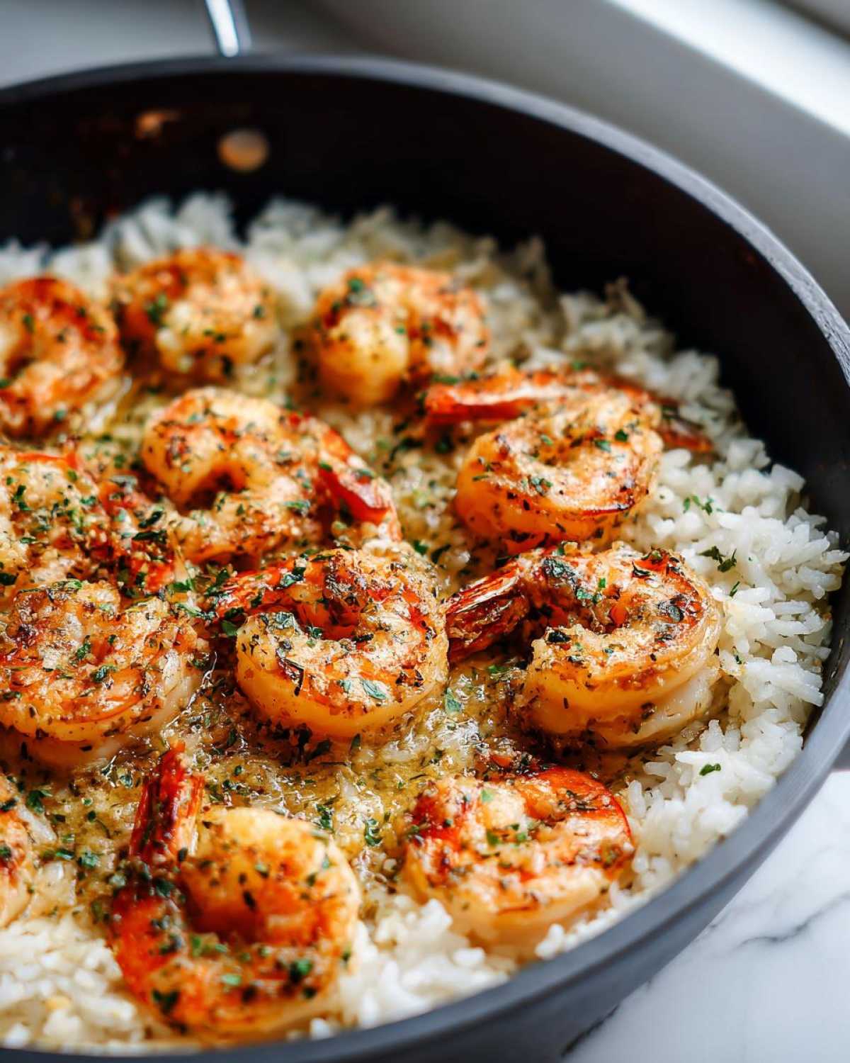 Close-up of seared Garlic Butter Shrimp with Rice Skillet, coated in garlic butter sauce and parsley.