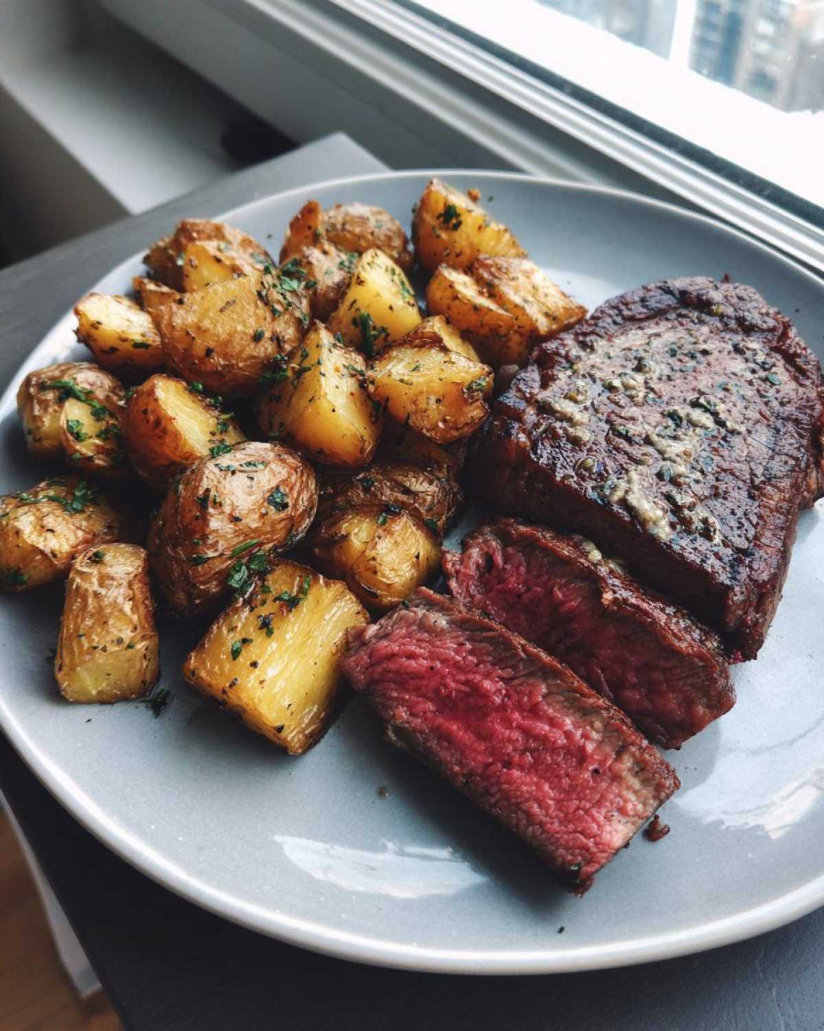 Plate of Garlic Butter Steak and Potatoes, showing a medium-rare sliced steak next to roasted potatoes.