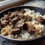Close-up of tender steak cubes mixed with white rice in a skillet, seasoned for Garlic Butter Steak and Rice Skillet Dinner.