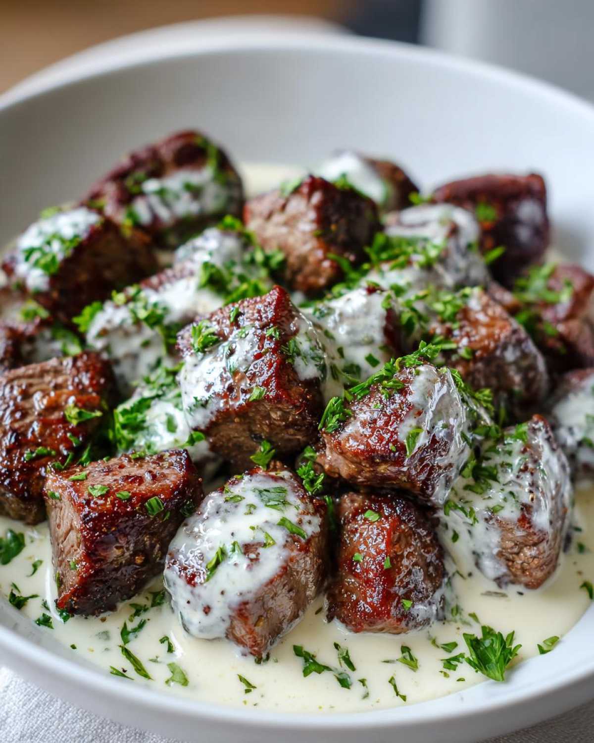 Close-up of seared Garlic Butter Steak Bites generously coated in creamy garlic sauce and sprinkled with fresh parsley.