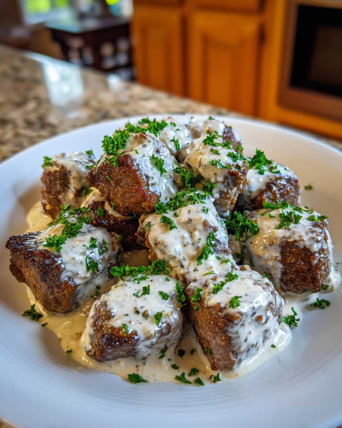 Close-up of seared Garlic Butter Steak Bites smothered in creamy garlic sauce and topped with fresh parsley.
