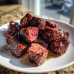 A pile of juicy Garlic Butter Steak Bites with crispy, dark edges and a medium-rare center served on a white plate.