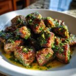 Close-up of juicy Garlic Butter Steak Bites generously coated in a bright green herb and garlic sauce.