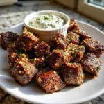 Plate of juicy Garlic Butter Steak Bites topped with minced garlic and herbs, served with a side of creamy garlic sauce.
