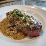 Perfectly cooked Garlic Butter Steak with Creamy Mushroom Sauce, showing a medium-rare center and parsley garnish.