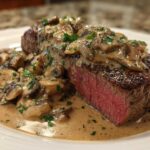 A perfectly cooked Garlic Butter Steak with Creamy Mushroom Sauce, showing a medium-rare interior and rich sauce.