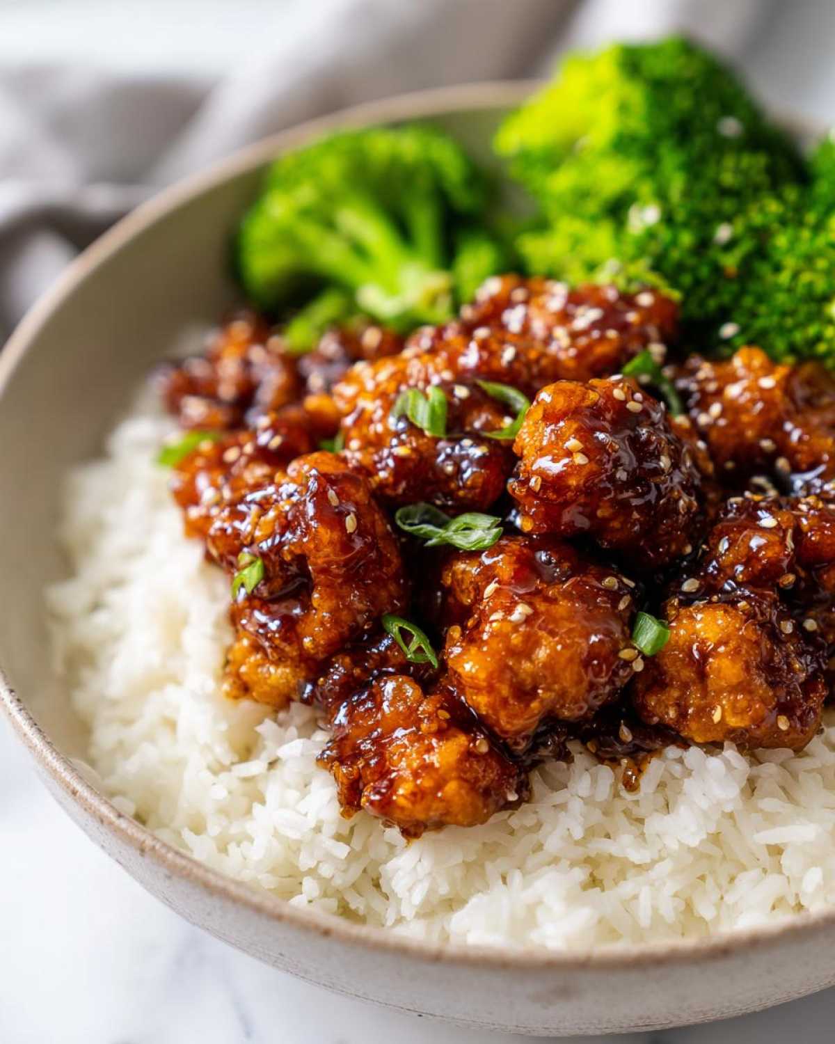 Close-up of Honey Garlic Chicken Bites coated in a rich glaze, served over white rice with steamed broccoli.