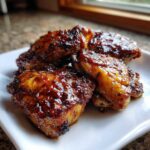 Close-up of three pieces of Honey Garlic Chicken Thighs with Crispy Skin, covered in a thick, shiny glaze.