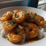 Plump shrimp coated in glossy honey garlic sauce served over white rice, garnished with parsley.