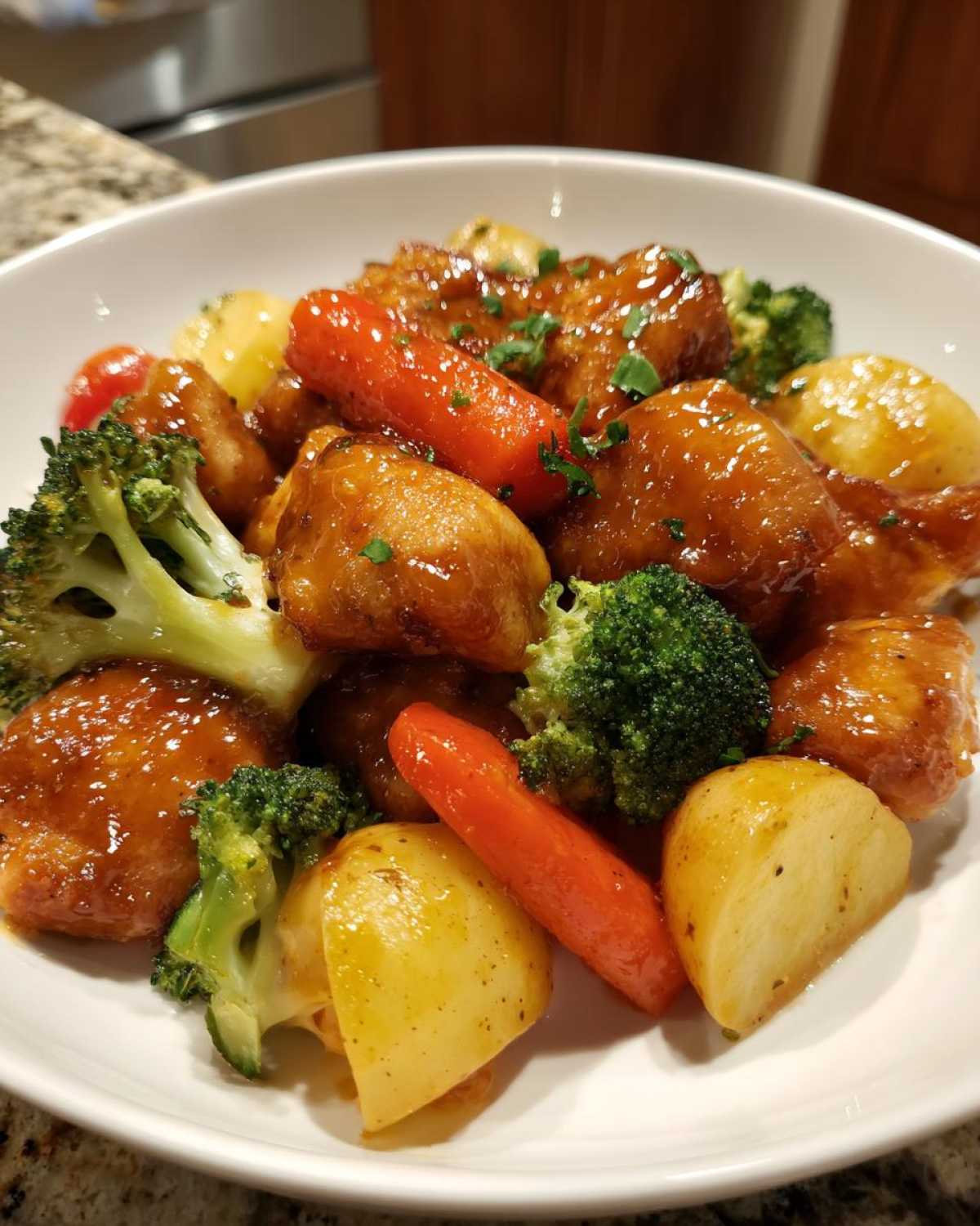 A serving of Honey Mustard Chicken Bake with roasted potatoes, carrots, and broccoli florets in a white bowl.