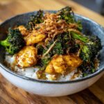 A close-up of a Honey Mustard Chicken Bowl with Rice, featuring glazed chicken pieces, roasted broccoli, and crispy fried onions.