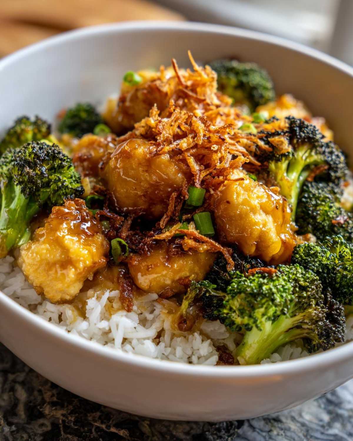 Close-up of a Honey Mustard Chicken Bowl with Rice, featuring glazed chicken pieces, roasted broccoli, and crispy fried onions.