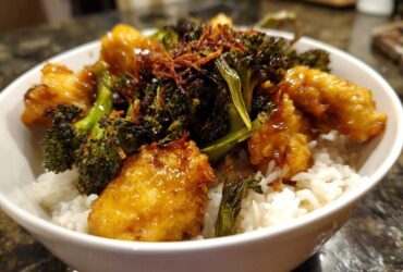 Close-up of a Honey Mustard Chicken Bowl with Rice, topped with crispy broccoli and fried onions.