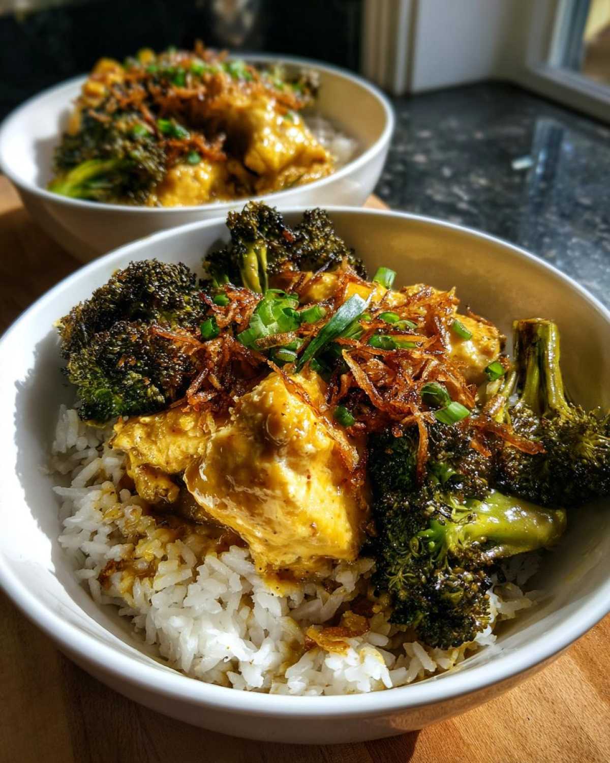 Close-up of a Honey Mustard Chicken Bowl with Rice, featuring saucy chicken, roasted broccoli, and crispy fried onions.