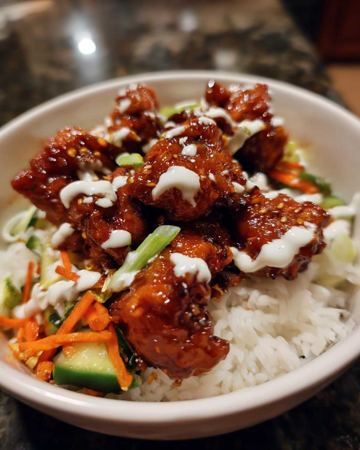 Close-up of a Honey Soy Chicken Bowl with Garlic Sauce, featuring glazed chicken pieces over rice and vegetables.